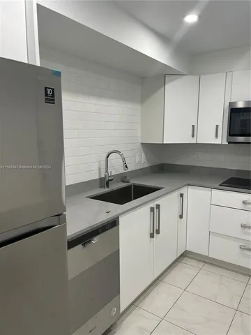 a kitchen with granite countertop white cabinets and sink
