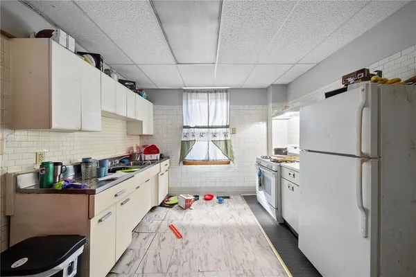 a kitchen with a refrigerator a sink dishwasher and white cabinets next to a window