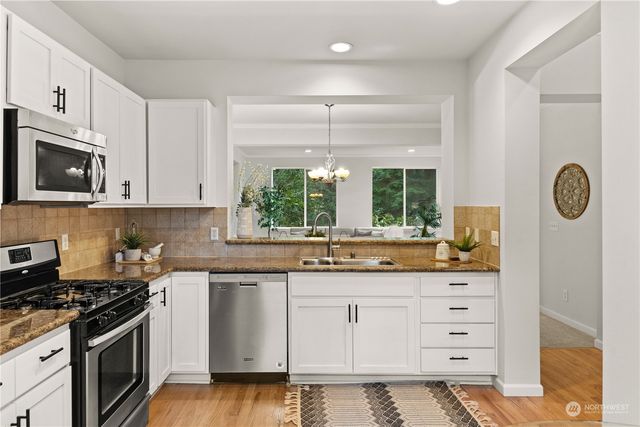 a kitchen with granite countertop a sink a stove and cabinets