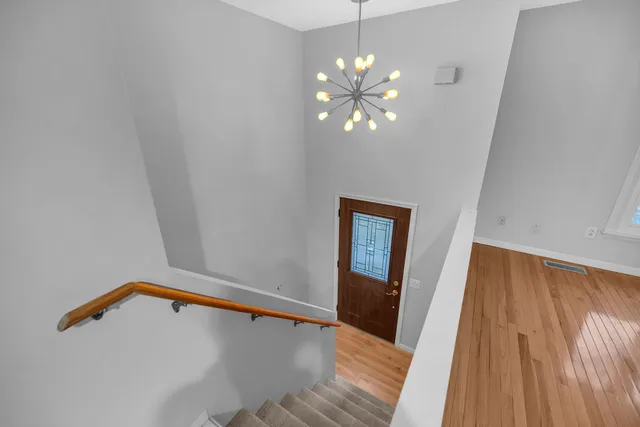 a view of a hallway with wooden floor and chandelier