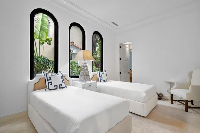 a bedroom with 2 bed and a large window