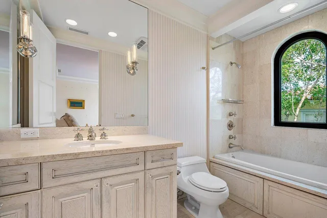 a bathroom with a toilet a sink a tub and mirror