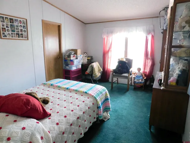 a bedroom with a bed table chair and window