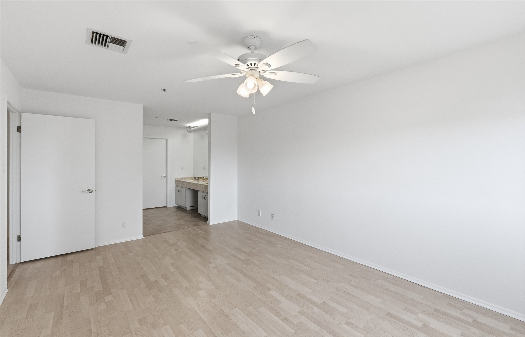 40 North Interstate Highway 35, Unit 7B1 Austin, TX 78701 - Photo 8 of 21 A well-lit primary bedroom with light-toned hardwood flooring and a ceiling fan.