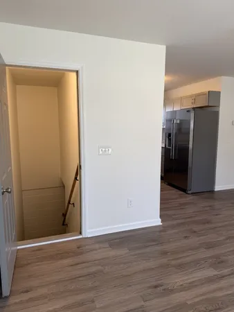 a view of a room with wooden floor and a refrigerator