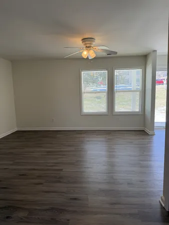 an empty room with wooden floor and windows