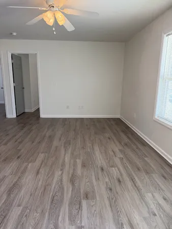 an empty room with wooden floor and windows