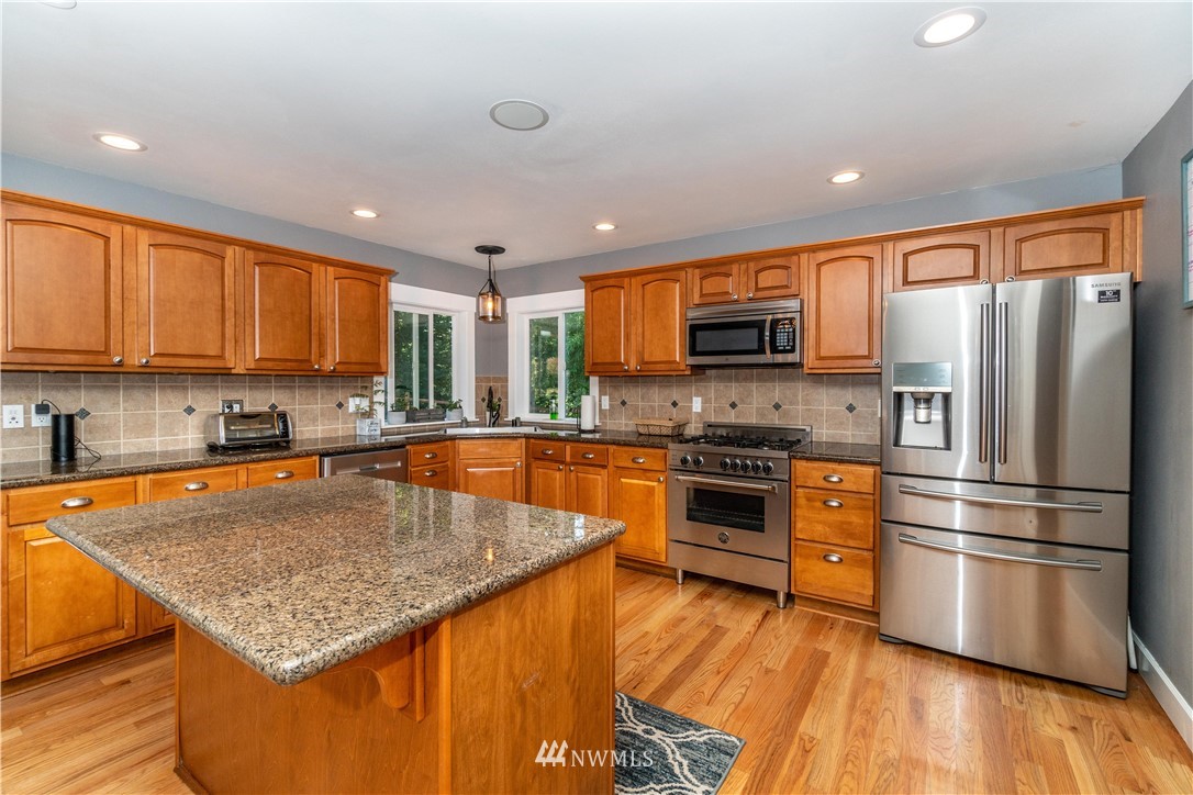 27515 Rose Road Arlington, WA 98223 - Photo 7 of 31 a kitchen with stainless steel appliances granite countertop a stove a sink dishwasher a refrigerator and a microwave oven with wooden floor