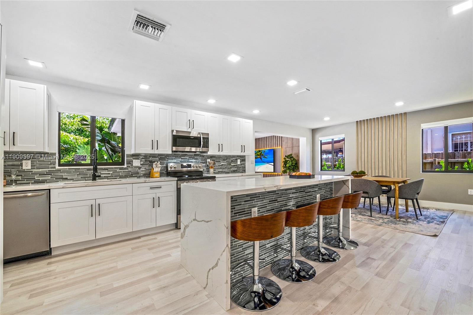 2585 Southwest 108th Avenue Miami, FL 33165 - Photo 11 of 11 a kitchen with stainless steel appliances granite countertop a stove top oven a sink dishwasher a dining table and chairs with wooden floor