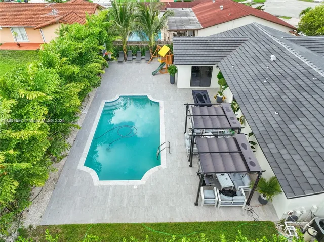a aerial view of a house with swimming pool and porch with furniture