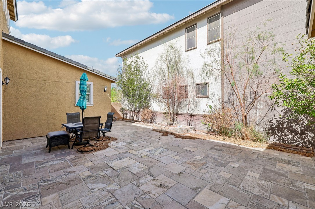 1100 East Sunset Road Henderson, NV 89011 - Photo 45 of 63 A spacious stone paver patio offers an inviting outdoor retreat bordered by mature plantings.