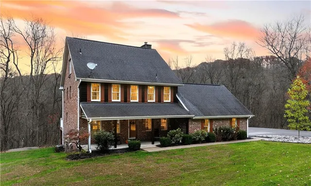 a front view of house with yard and trees in the background