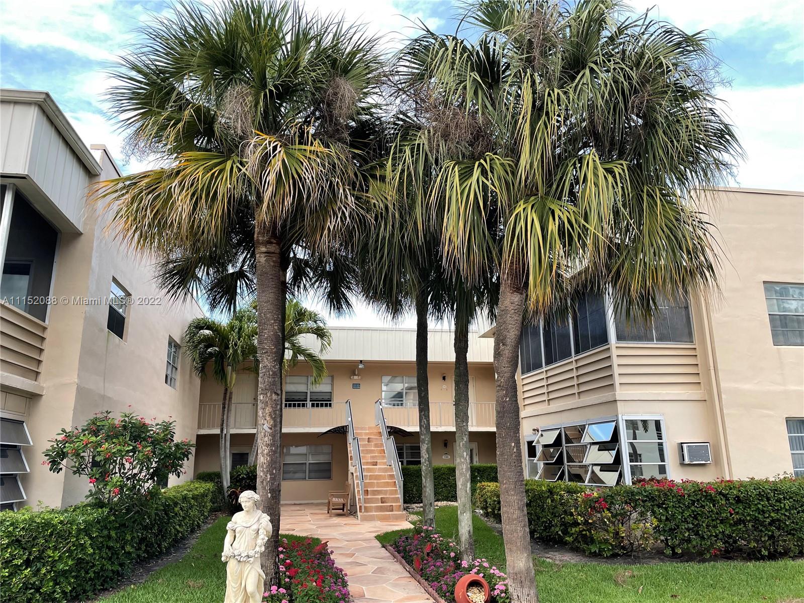 a front view of multi story residential apartment building with yard and green space