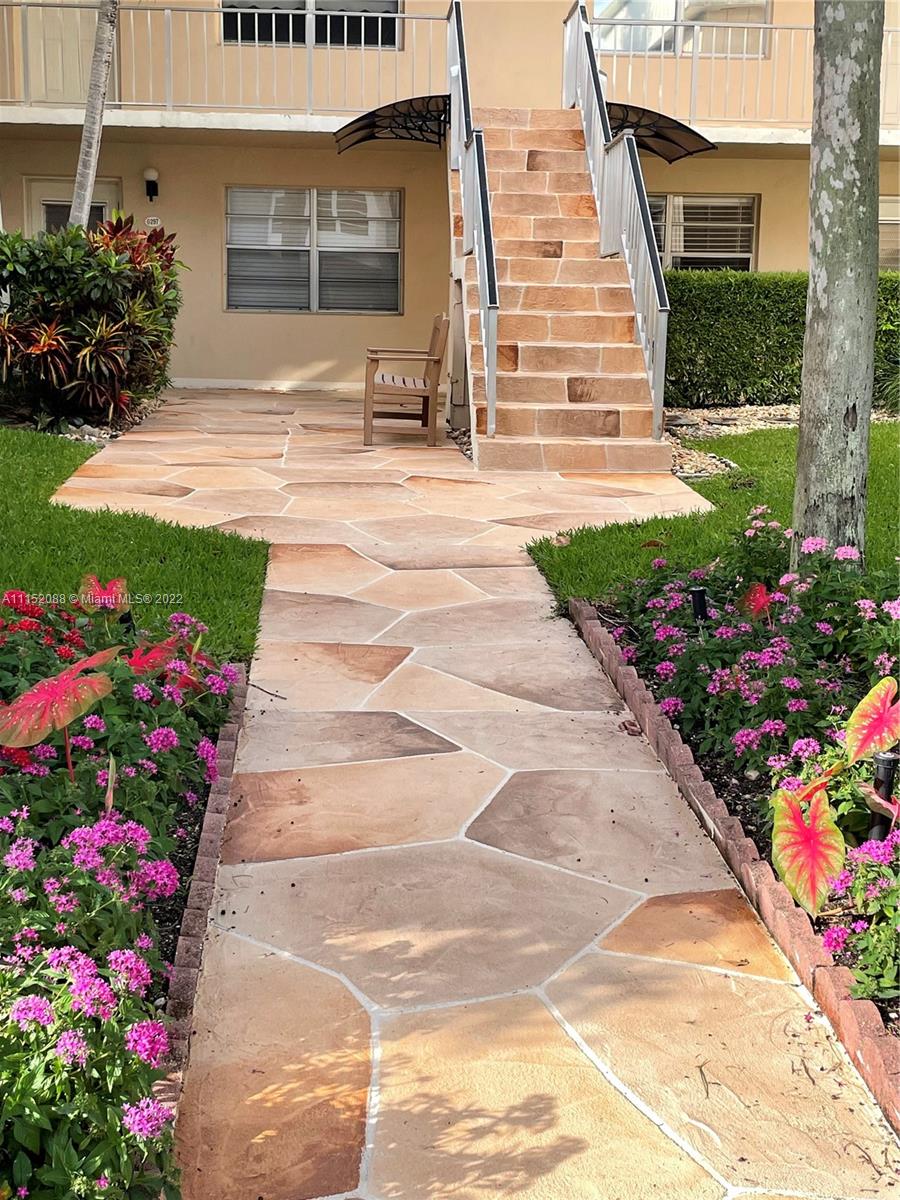 Kings Point Delray Beach, FL 33484 - Photo 3 of 69 a front view of a house with a yard and flowers