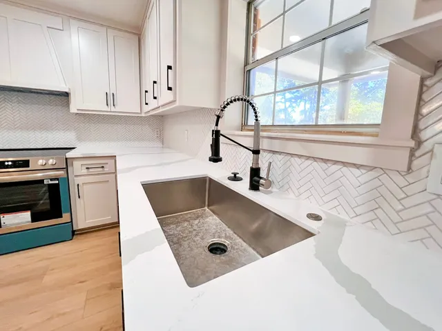 a kitchen with sink a stove and a microwave oven with white cabinets