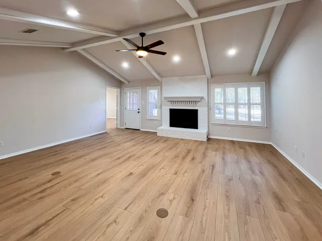 a view of an empty room with window and wooden floor