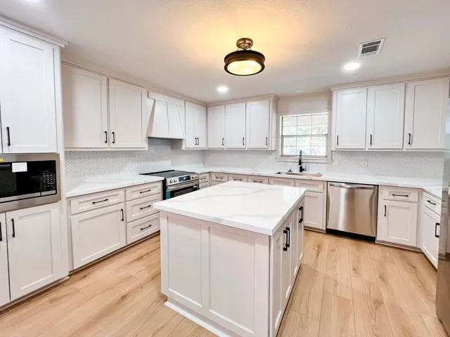 a kitchen with granite countertop a sink white cabinets and white stainless steel appliances