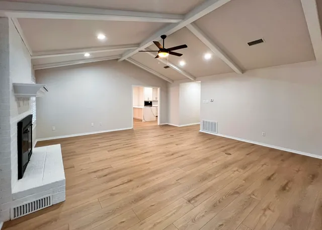 an empty room with wooden floor a ceiling fan a fireplace and wooden floor