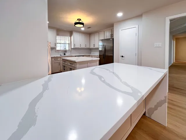 a view of a kitchen with kitchen island a sink stainless steel appliances and cabinets