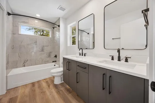 a bathroom with a double vanity sink toilet mirror and bathtub