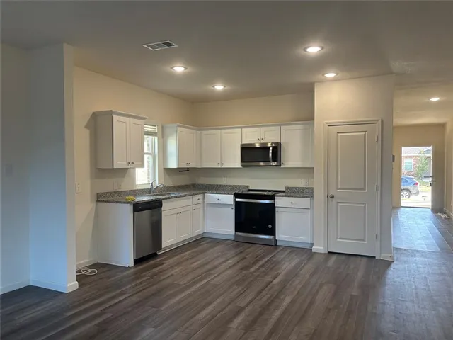 a large kitchen with stainless steel appliances granite countertop a stove and a sink