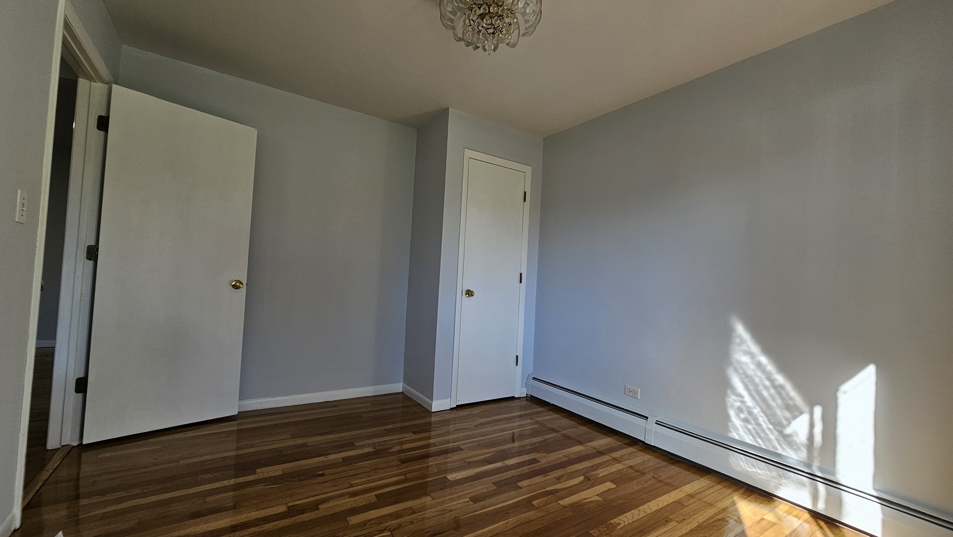 9588 Terrace Place, Unit 1C Des Plaines, IL 60016 - Photo 10 of 13 a view of an empty room with wooden floor and a window