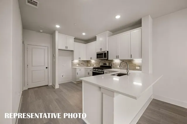 a kitchen with stainless steel appliances a sink a stove a refrigerator cabinets and a center island