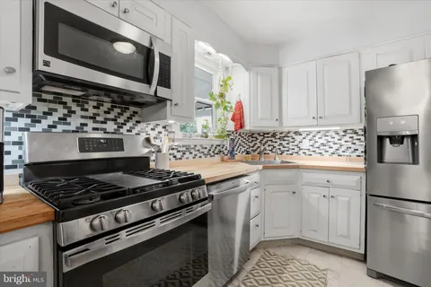 a kitchen with stainless steel appliances a stove a microwave a sink and cabinets