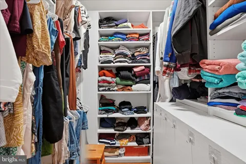 a view of walk in closet with clothes and shoes