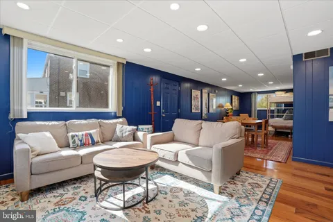 a living room with furniture a glass table and kitchen view