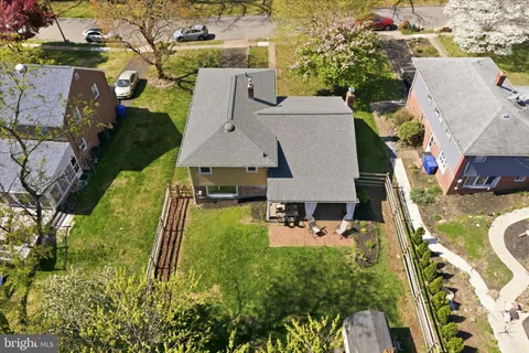 an aerial view of a house with swimming pool and large trees