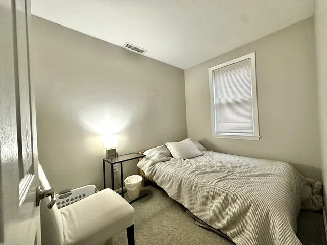 a bedroom with a bed and a refrigerator