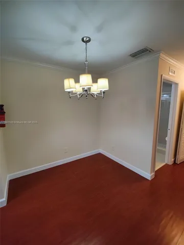 a view of an empty room with a chandelier fan