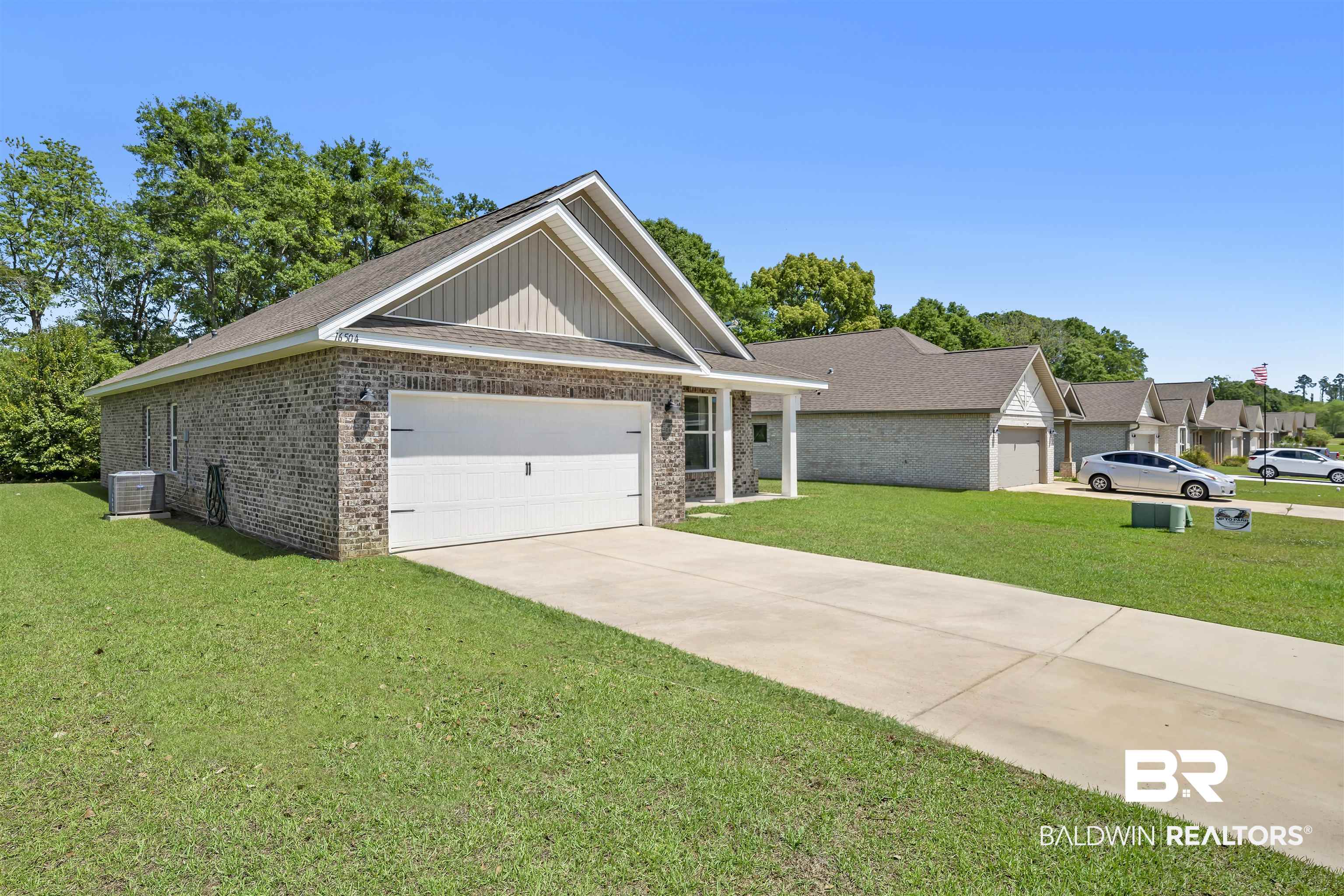 16504 Prado Loop Loxley, AL 36551 - Photo 5 of 45 View of front facade featuring brick siding, a front yard, an attached garage, driveway, and roof with shingles