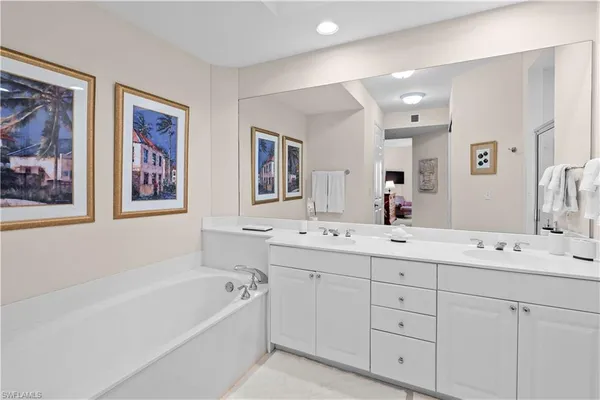 a bathroom with a double vanity sink mirror and bathtub