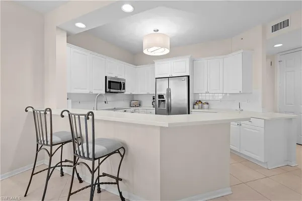 a kitchen with stainless steel appliances a refrigerator a stove a dining table and chairs