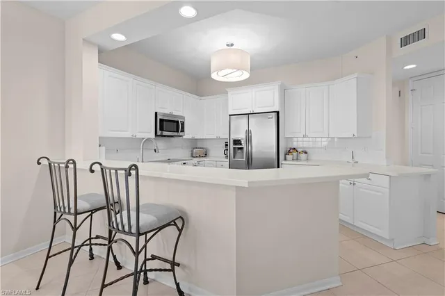 a kitchen with stainless steel appliances a refrigerator a stove a dining table and chairs