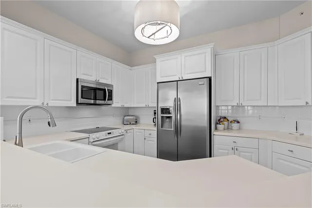 a kitchen with stainless steel appliances granite countertop a sink a stove a refrigerator cabinets and black appliances