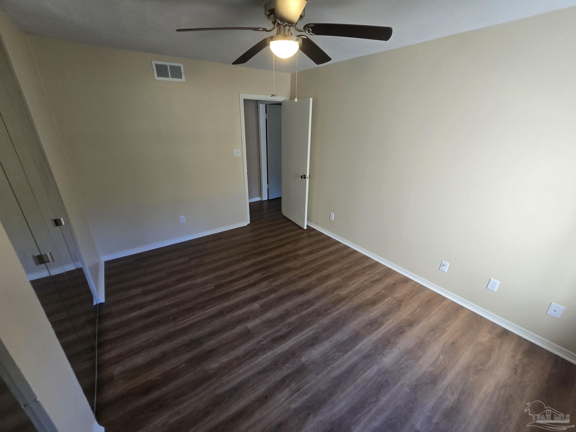 2303 West Michigan Avenue, Unit B10 Pensacola, FL 32526 - Photo 8 of 25 a view of an empty room with wooden floor and a ceiling fan