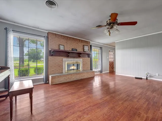 a view of an empty room with a window and wooden floor