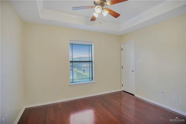an empty room with wooden floor chandelier fan and windows