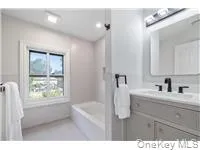 a bathroom with a bathtub a sink a window and a mirror