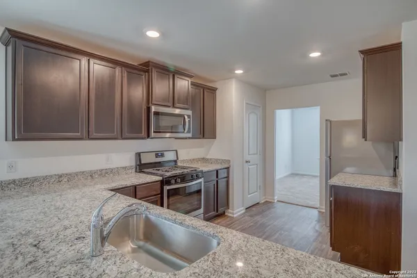 a kitchen with granite countertop stainless steel appliances a stove sink and refrigerator