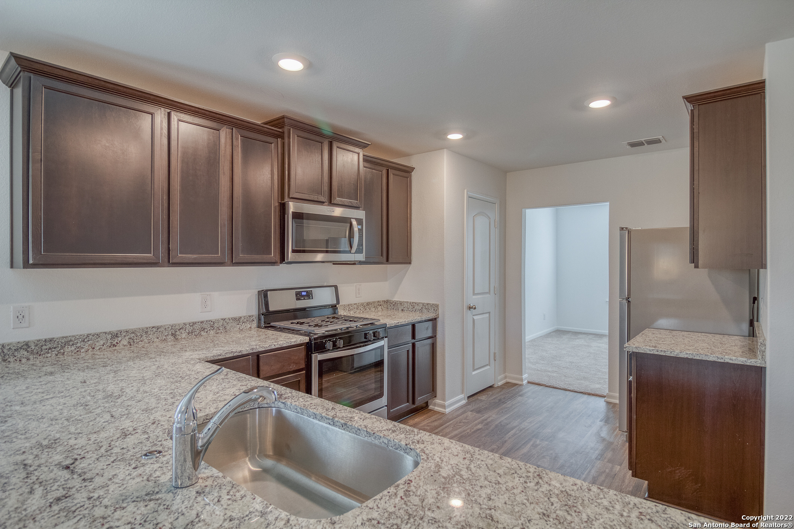 3055 Jackson Summit Converse, TX 78109 - Photo 13 of 31 a kitchen with granite countertop stainless steel appliances a stove sink and refrigerator