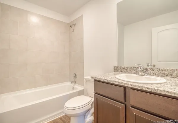 a bathroom with a granite countertop sink toilet mirror and bathtub