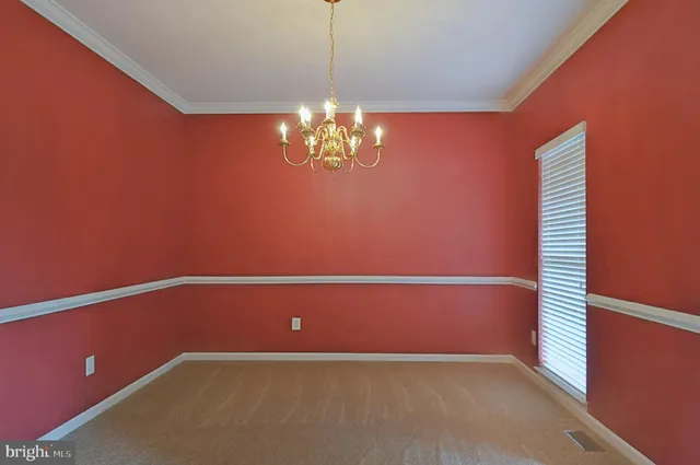 a view of an empty room with a chandelier fan