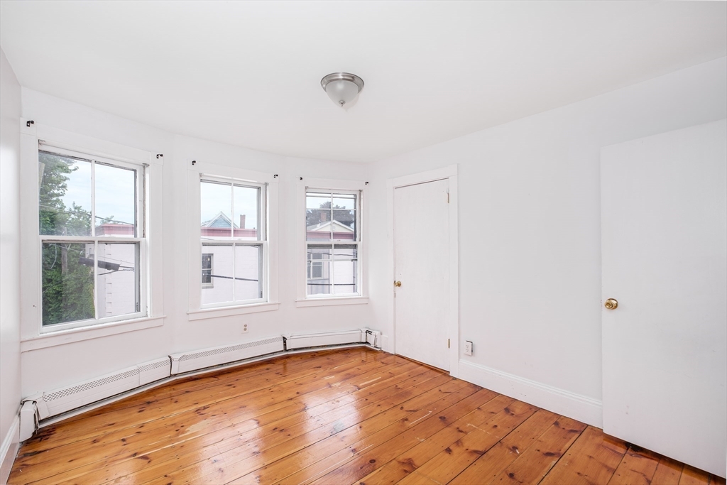 12 Kilby Street, Unit 2R Somerville, MA 02143 - Photo 7 of 19 an empty room with wooden floor and windows