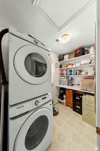1225 North Dixie Downs Road, Unit 161 St. George, UT 84770 - Photo 15 of 21 Dedicated laundry area featuring stacked appliances, overhead shelving, built-in countertop, and patterned flooring