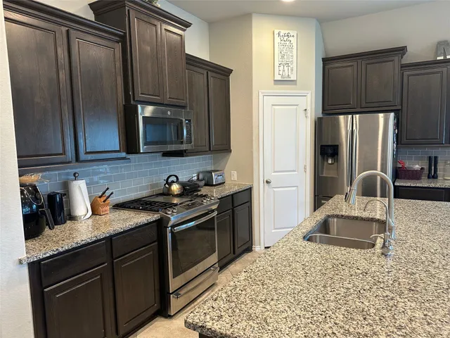 a kitchen with granite countertop a refrigerator stove and sink