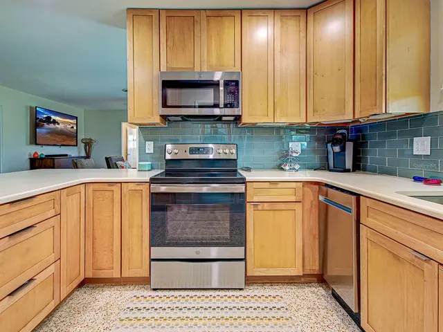 a kitchen with stainless steel appliances granite countertop a stove a sink and a microwave